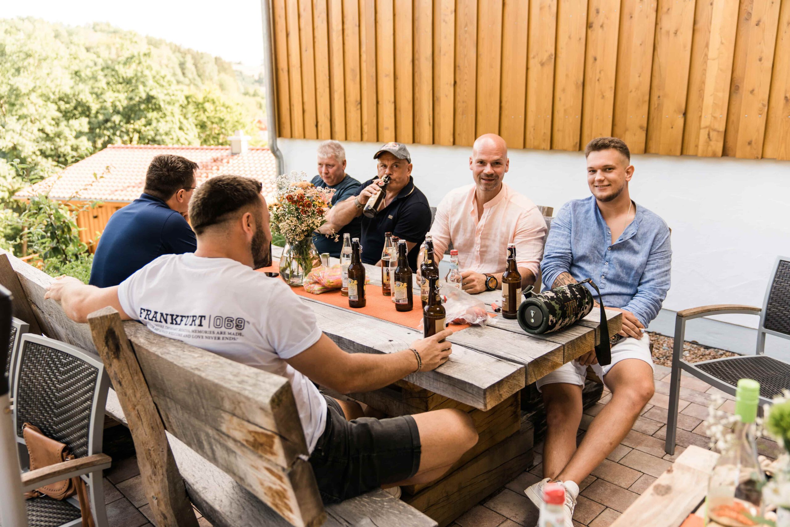 Gruppe voller Männer sitzen am Tisch, hören Musik und trinken Bier und Apfelwein